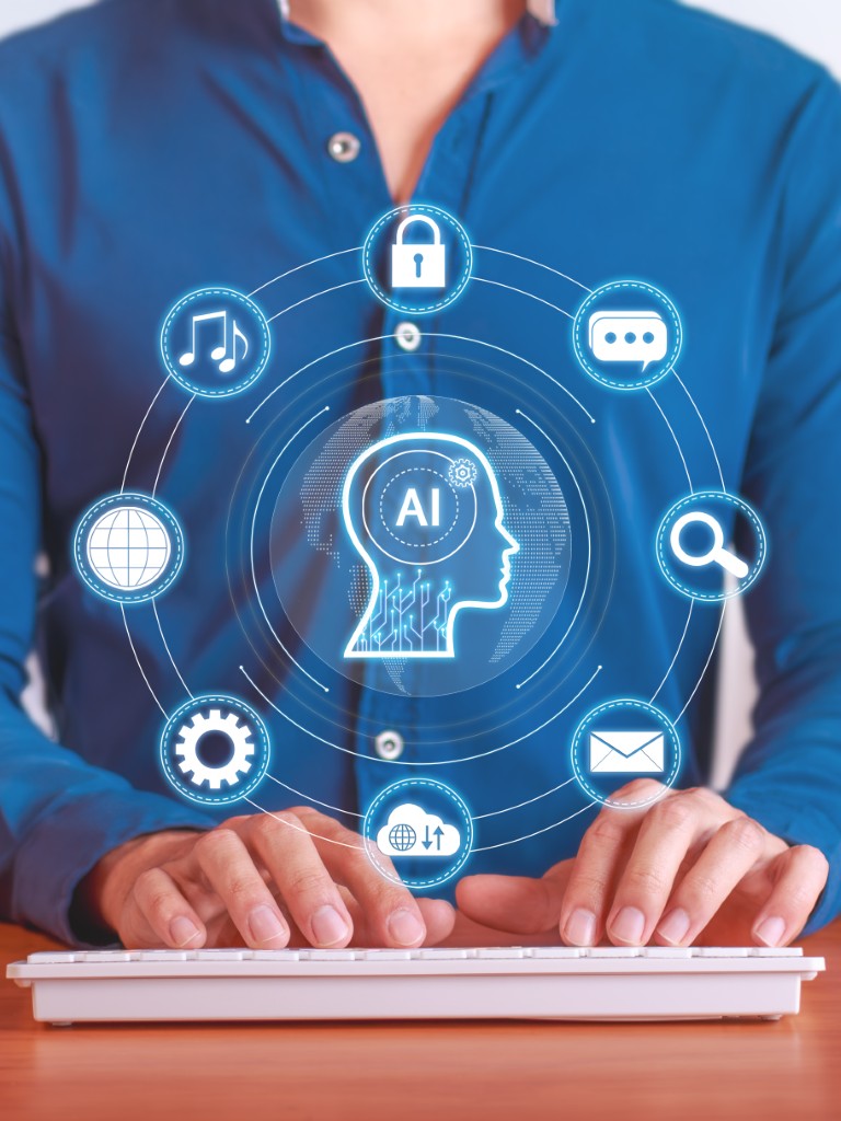 Eine Person tippt auf einem Keyboard. Drüber schwebt ein Hologramm mit AI Anwendungen.